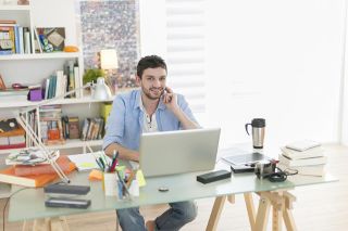 Foto: Mann sitzt vor Laptop in Arbeitszimmer